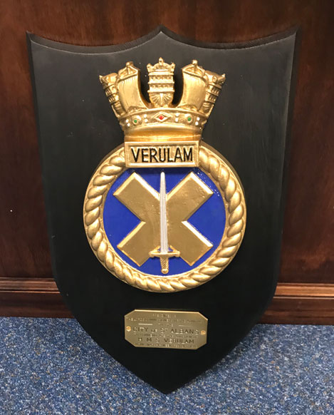 The replica crest of HMS Verulam remounted on a woode shield with the enscribed plate
